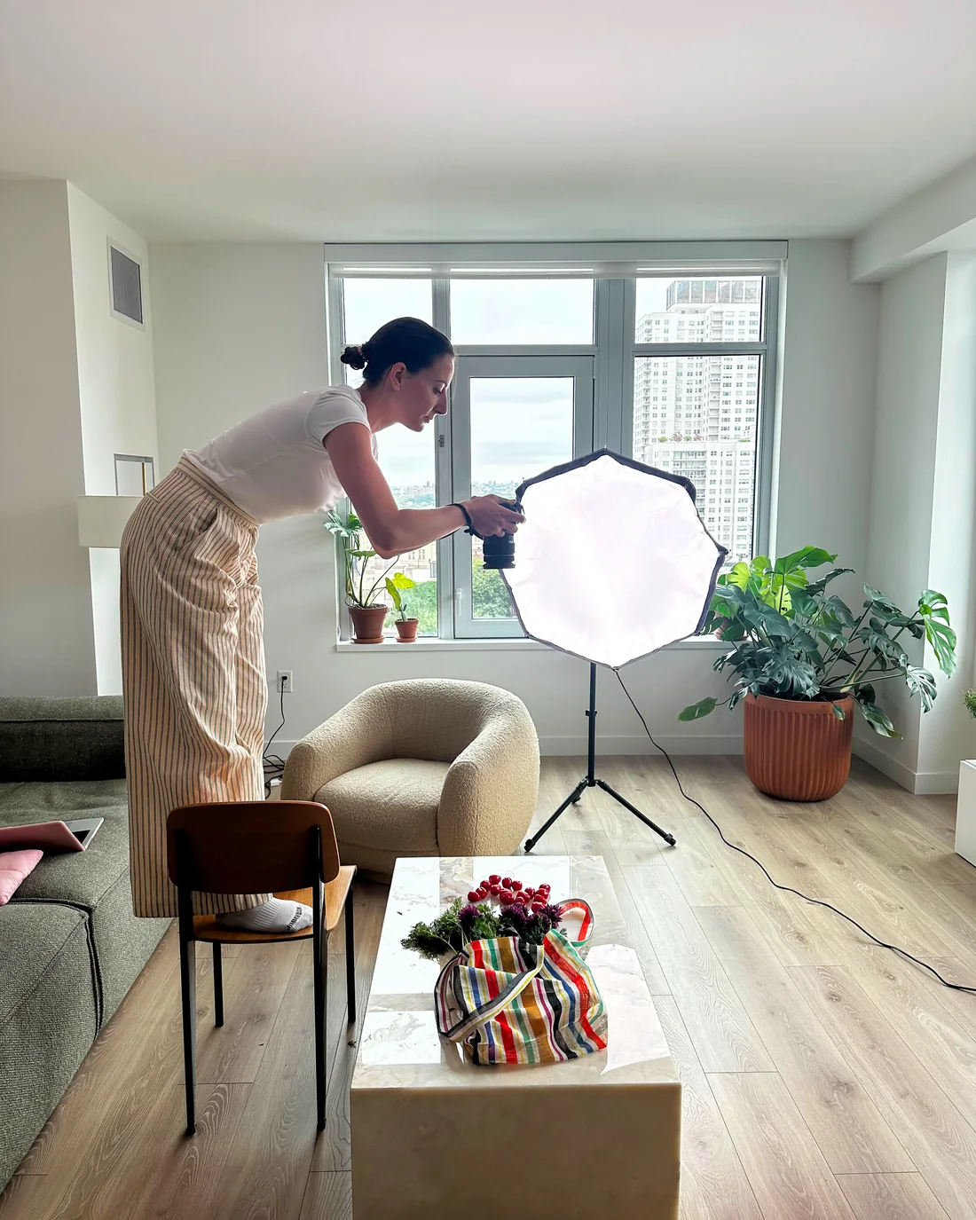 Angela Kunder règle une boîte à lumière au-dessus du décor, dans un appartement à New York