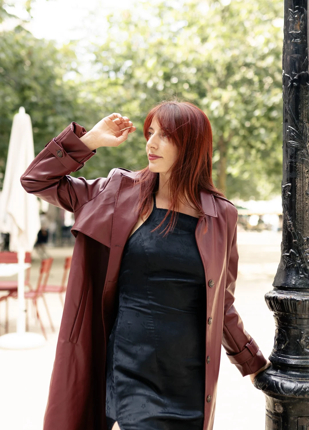 Portrait d'Angela Kunder, trench bordeaux, sur une place parisienne