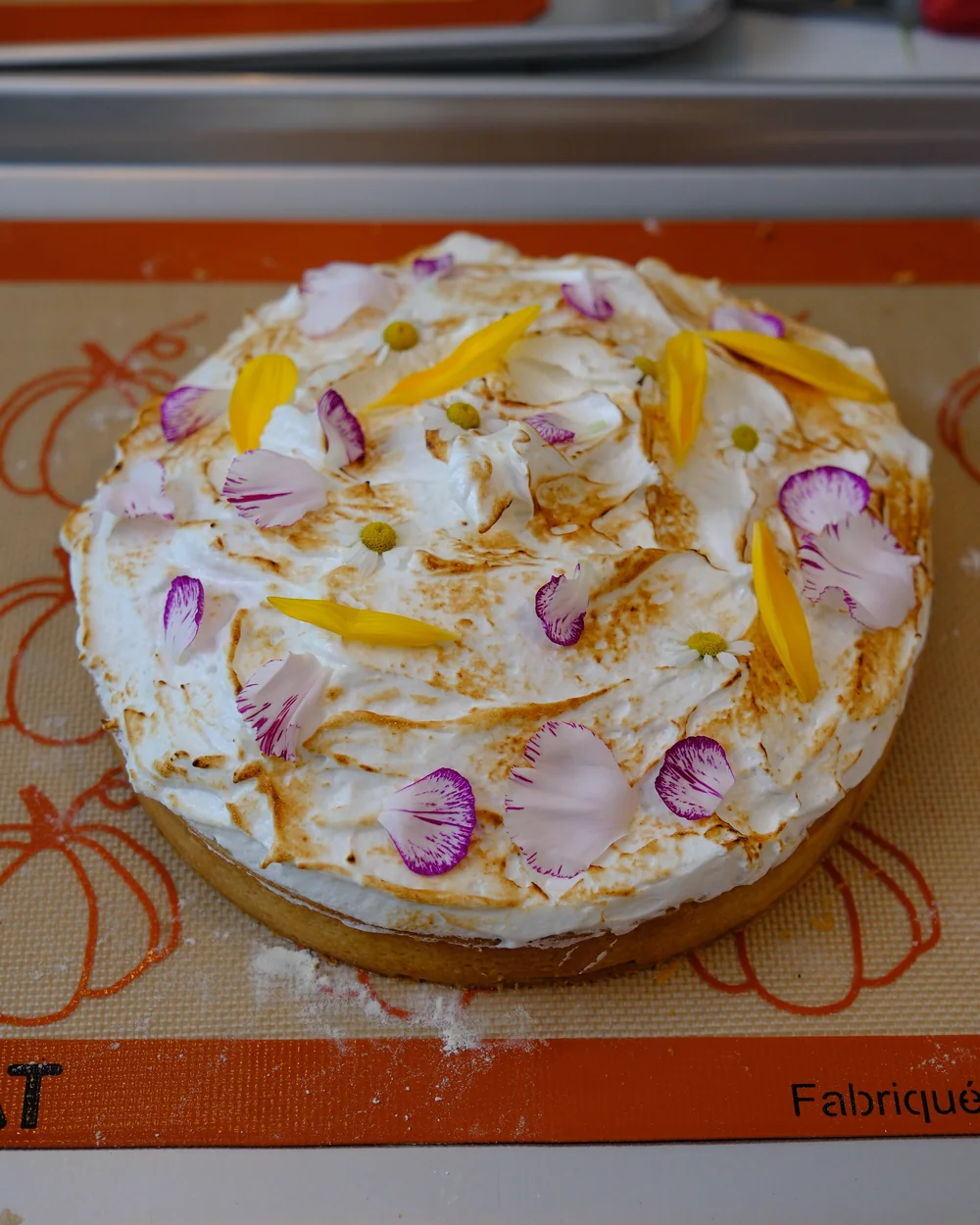 Tarte au citron meringuée décorée de pétales et de fleurs comestibles