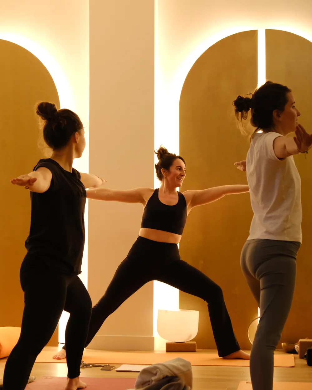 Cours de yoga, posture du guerrier devant des arches dorées
