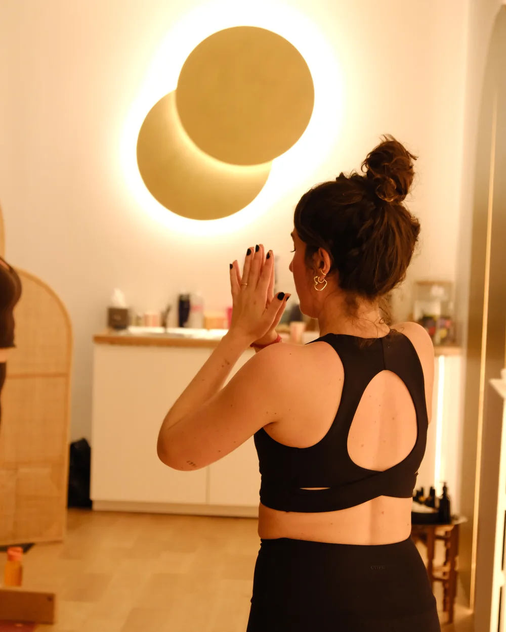 Mains jointes devant une applique dorée, studio de yoga